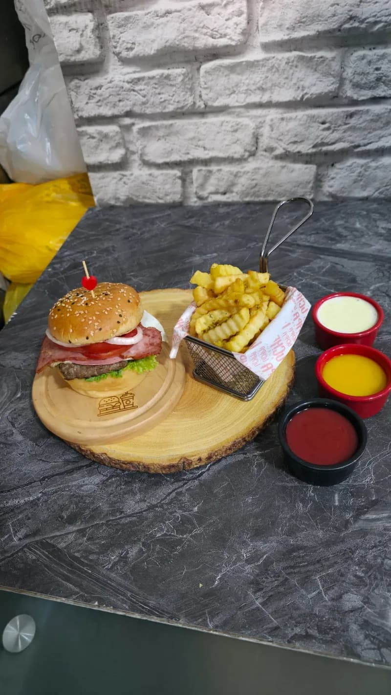 Hamburguesa artesanal con papas fritas en tabla de madera en Comas