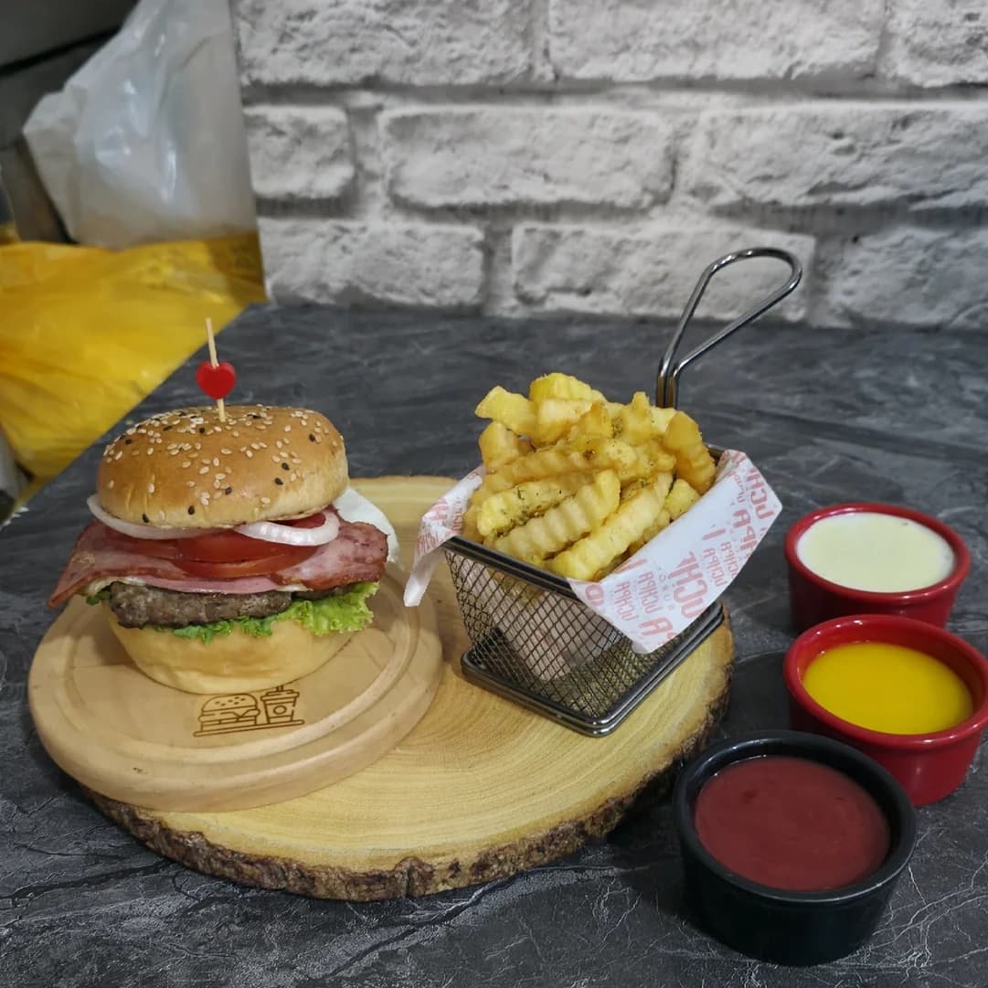 Hamburguesa artesanal con papas fritas en tabla de madera en UCHPA Burgers Comas